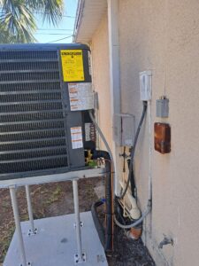 GrandAire outdoor air conditioner condenser installed on an elevated hurricane-resistant equipment stand with concrete pad