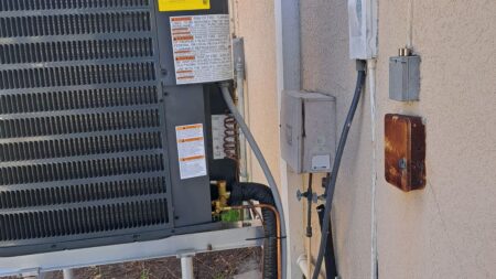 GrandAire outdoor air conditioner condenser installed on an elevated hurricane-resistant equipment stand with concrete pad