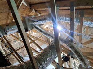 Insulated flexible HVAC ducts connected to a supply plenum in a residential attic installation