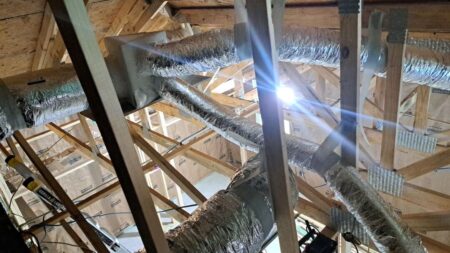 Insulated flexible HVAC ducts connected to a supply plenum in a residential attic installation