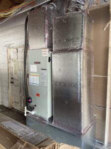 Commercial HVAC air handler suspended from the ceiling with insulated ductwork during professional installation