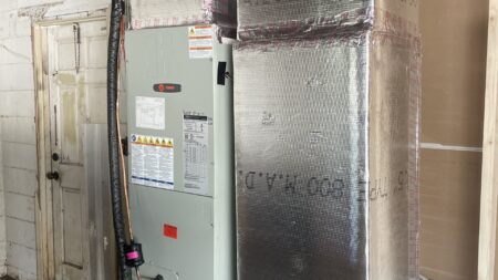 Commercial HVAC air handler suspended from the ceiling with insulated ductwork during professional installation