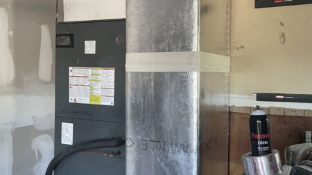 Residential air conditioner condenser installation on raised platform with professional refrigerant line routing