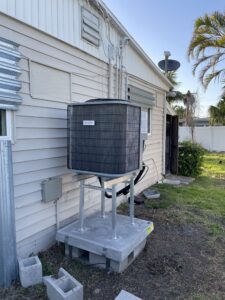 New high-efficiency outdoor AC condenser installed on an elevated stand with concrete pad in Tampa, FL