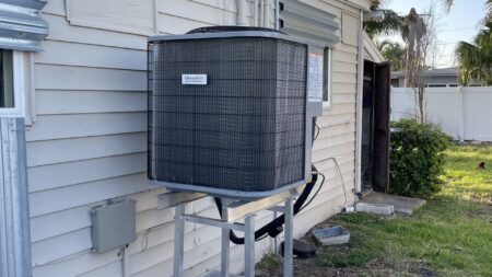 New high-efficiency outdoor AC condenser installed on an elevated stand with concrete pad in Tampa, FL