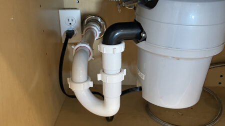 Professional garbage disposal installation with plumbing connections