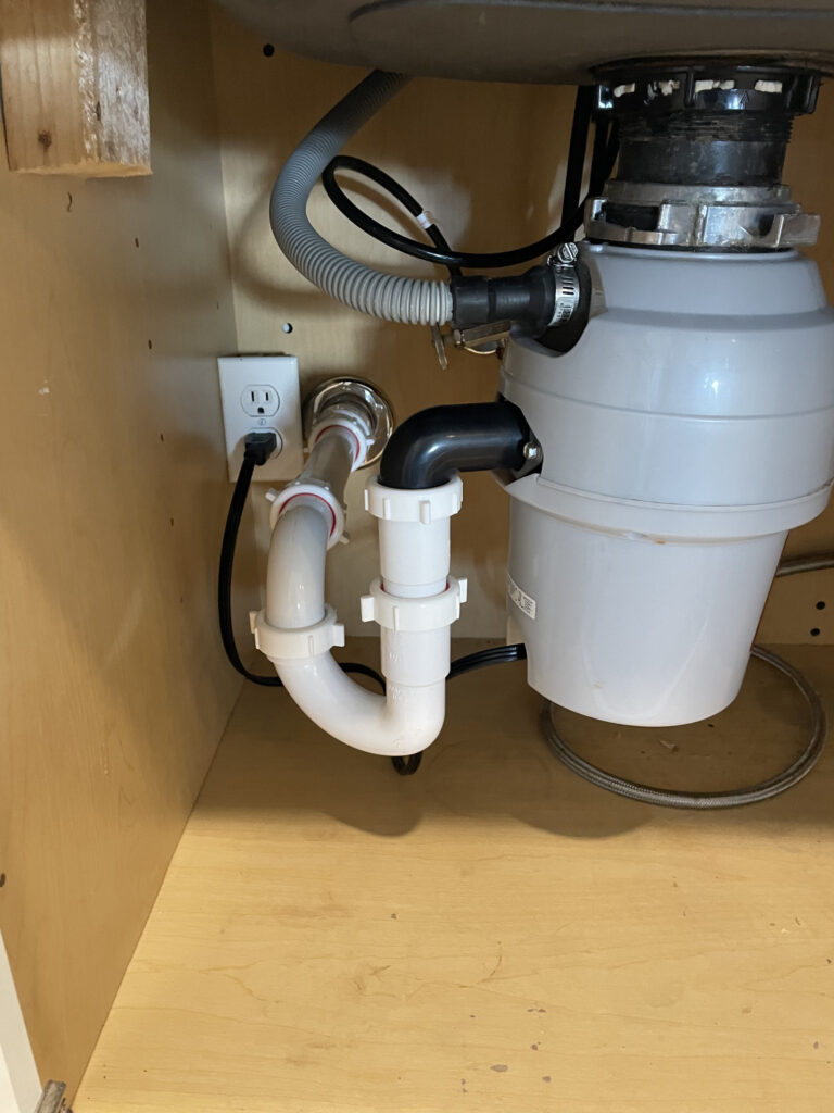 Professional garbage disposal installation with plumbing connections